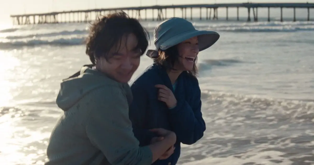 Lucy Liu e Lawrence Shou sorrindo na praia em uma cena do filme Rosemead (2025), drama baseado em uma história real dirigido por Eric Lin.