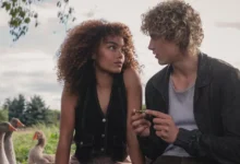 Joseph Zada e Whitney Peak em cena do Teaser de Jogos Vorazes - Amanhecer na Colheita, conversando em ambiente rural com gansos ao fundo