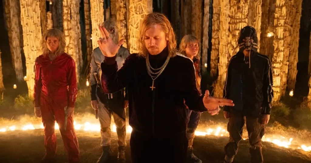 elenco de exterminio o templo dos ossos Maura Bird, Jack O'Connell e Erin Kellyman em um ritual sombrio na floresta no filme Extermínio: O Templo dos Ossos, parte do elenco de Extermínio: O Templo dos Ossos.