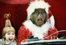 Cena do filme O Grinch (2000) com o Grinch vestido de Papai Noel e Cindy Lou Who sorrindo ao seu lado; imagem utilizada no especial “O elenco de ‘O Grinch’ 25 anos depois”.