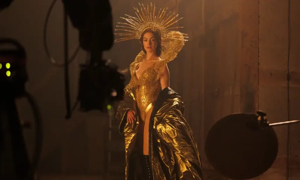 filme mother mary 2026 Anne Hathaway caracterizada em uma luxuosa roupa dourada no set de “Mother Mary”, drama da A24 dirigido por David Lowery.