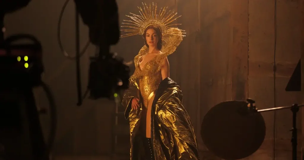 filme mother mary 2026 Anne Hathaway caracterizada em uma luxuosa roupa dourada no set de “Mother Mary”, drama da A24 dirigido por David Lowery.