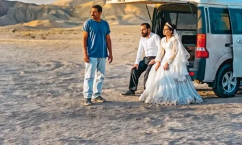 Cena do filme iraniano “Foi Apenas um Acidente”, destaque entre as estreias de 04 de dezembro de 2025, mostrando um casal vestido para casamento e um homem ao lado de uma van no deserto.