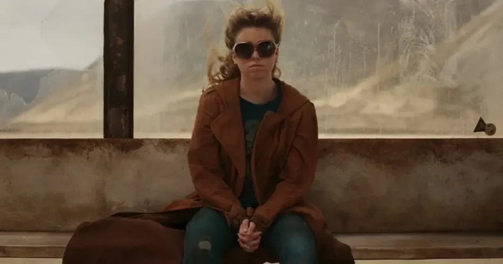 Milly Alcock como Supergirl sentada em uma estação desértica no trailer do filme da DC.