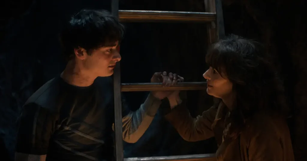 stranger things 5 volume 2 elenco 1 Joyce Byers e Will Byers em cena dramática do trailer de Stranger Things 5 Volume 2, com Joyce segurando a mão de Will através de uma janela em ambiente escuro