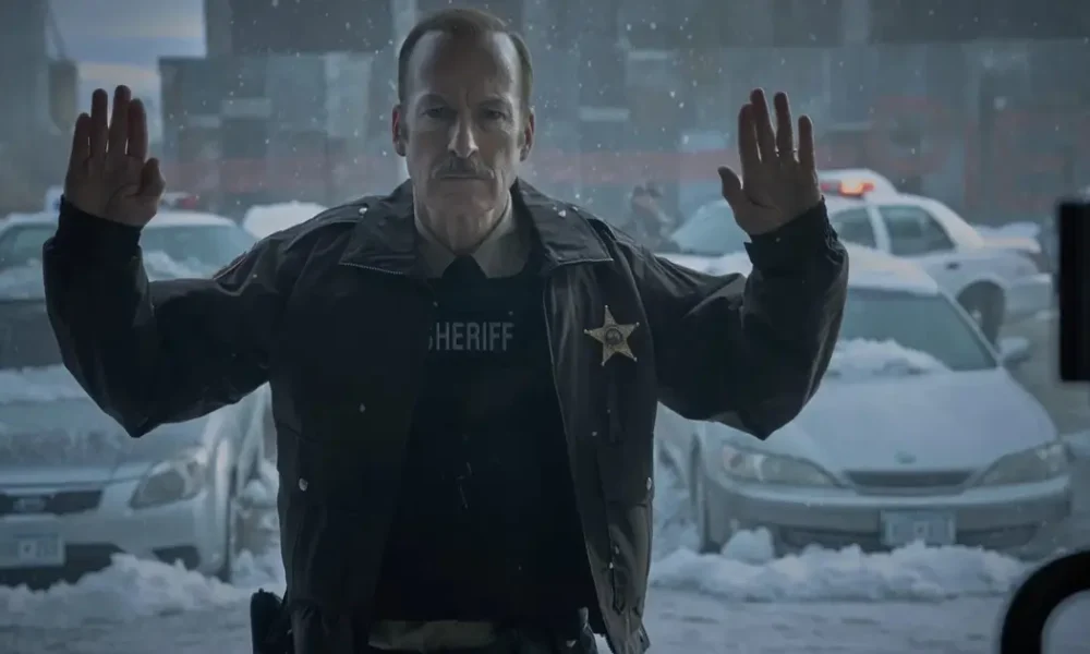 Bob Odenkirk como Ulysses em cena do teaser de Normal (2025), thriller de ação dirigido por Ben Wheatley, com o personagem usando uniforme de xerife em meio a um cenário urbano coberto de neve.