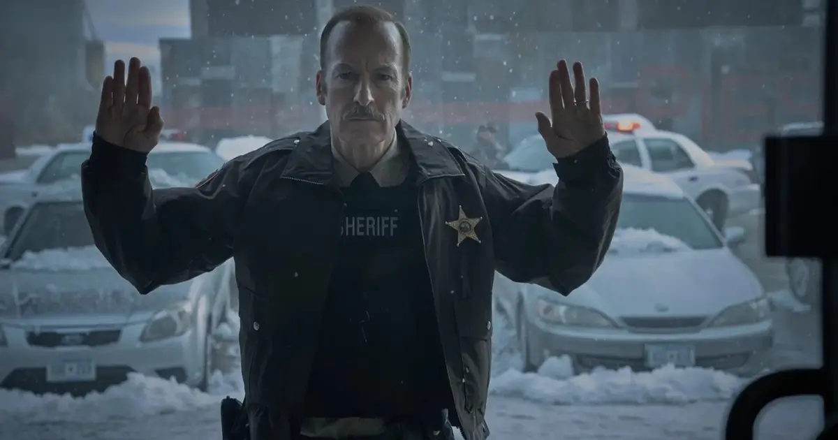Bob Odenkirk como Ulysses em cena do teaser de Normal (2025), thriller de ação dirigido por Ben Wheatley, com o personagem usando uniforme de xerife em meio a um cenário urbano coberto de neve.