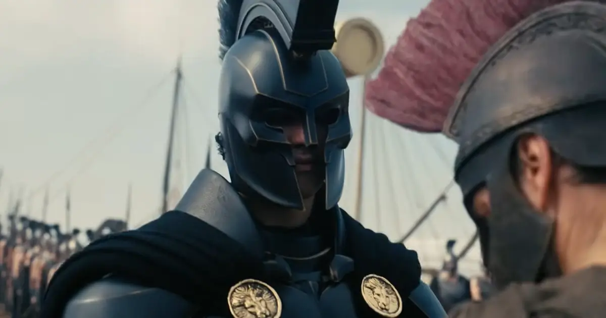 Cena do trailer de A Odisseia (The Odyssey), novo filme de Christopher Nolan, com guerreiro usando armadura e capacete em cenário épico inspirado na Grécia Antiga