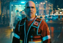Luis Tosar usando uniforme de equipe de emergência sob chuva, em cena noturna da série espanhola da Netflix Salvador.