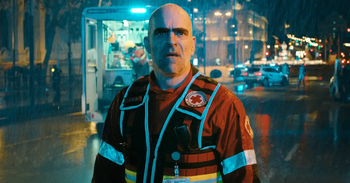 Luis Tosar usando uniforme de equipe de emergência sob chuva, em cena noturna da série espanhola da Netflix Salvador.