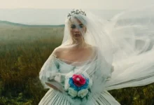 cinema 12 de fevereiro de 2026 Margot Robbie em cena de “O Morro dos Ventos Uivantes” (2026), vestida de noiva em campo aberto — uma das estreias de 12 de fevereiro de 2026.