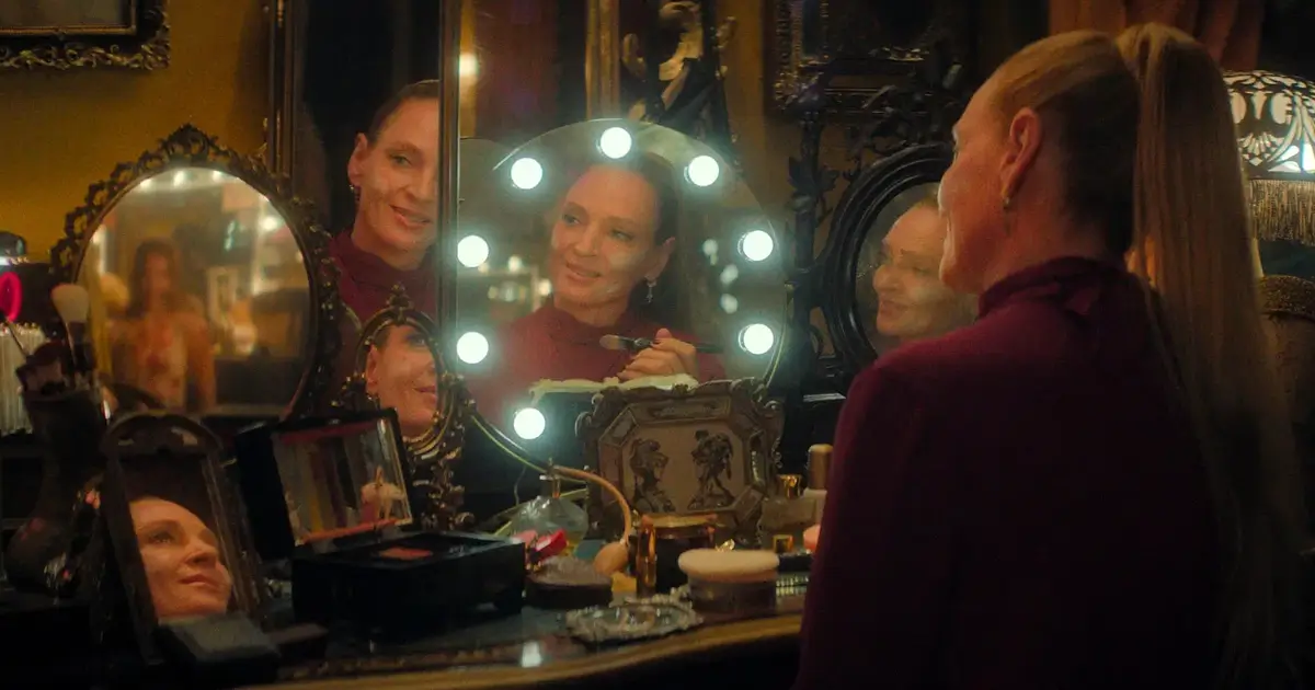 Uma Thurman em cena de “Linda e Letais” (2026), sentada em frente ao camarim iluminado, no filme de ação dirigido por Vicky Jewson para o Prime Video.