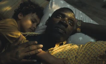 Omar Sy em cena emocional de O Caso dos Estrangeiros, deitado com uma criança