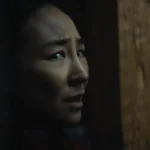 Greta Lee em cena de “A Última Casa” (2026), personagem aparece assustada em ambiente escuro no filme de ficção científica da Netflix