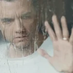 Wagner Moura em cena nas primeiras imagens de “A Última Casa” (2026), personagem observa através de vidro molhado em momento de tensão no terror da Netflix