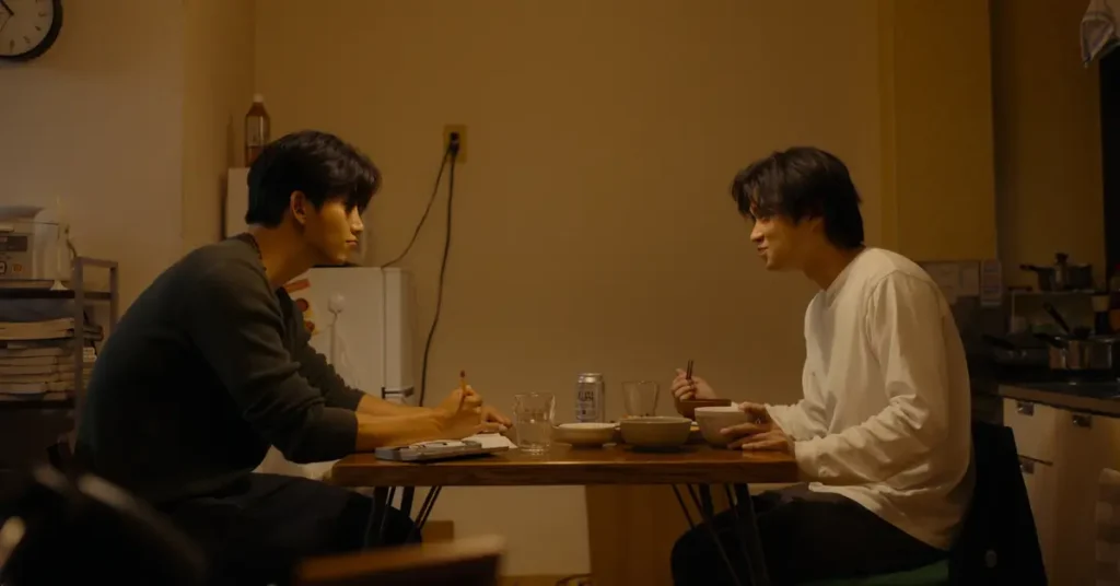 Taecyeon e Hayato Isomura em cena do elenco de Alma Gêmea (2026), série da Netflix, durante refeição em momento intimista
