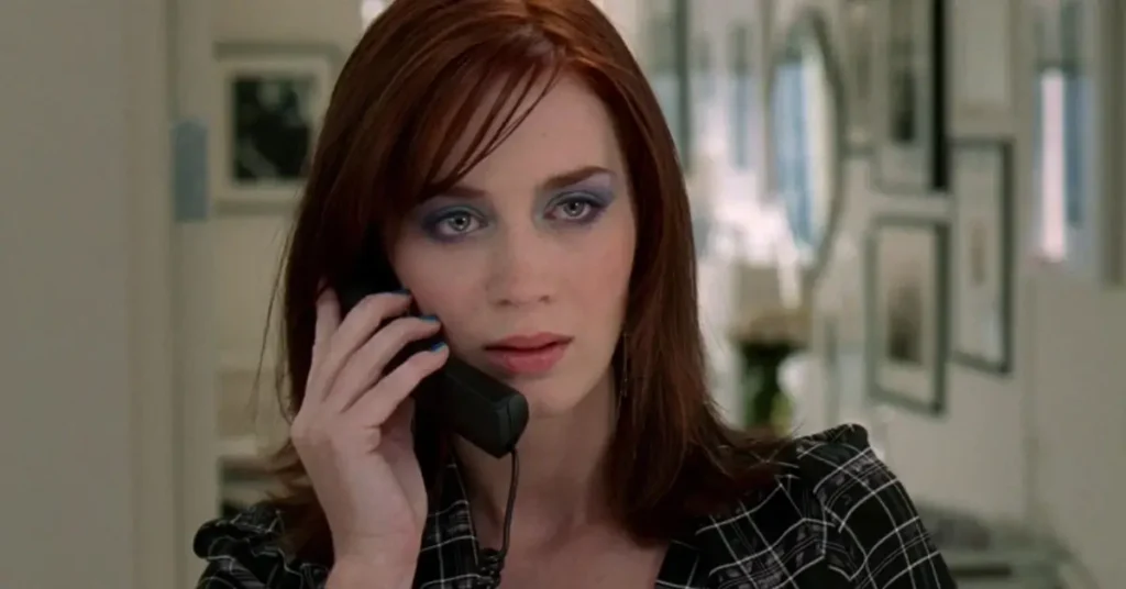 Emily Blunt como Emily Charlton falando ao telefone em O Diabo Veste Prada com expressão séria e irônica