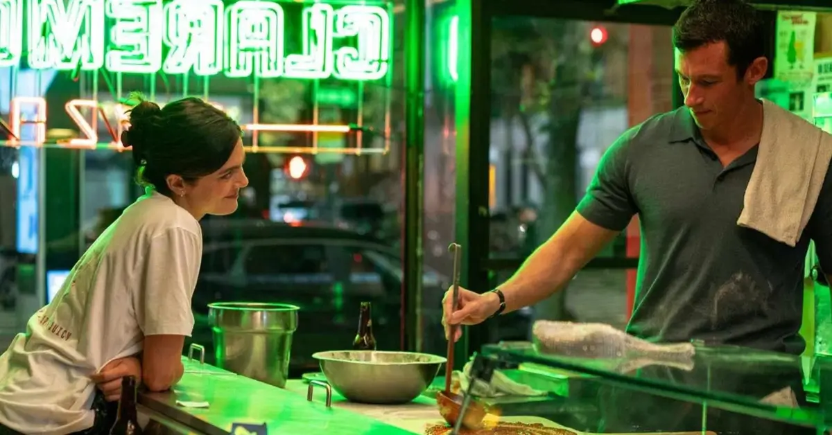Monica Barbaro observa Callum Turner preparando comida em um restaurante na cena do trailer de Só Por Uma Noite (2026)