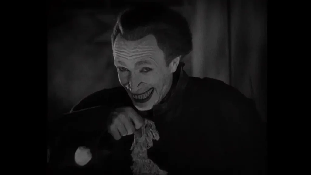 Gwynplaine, personagem interpretado por Conrad Veidt em O Homem que Ri (1928), com o sorriso deformado que inspirou visualmente o Coringa.