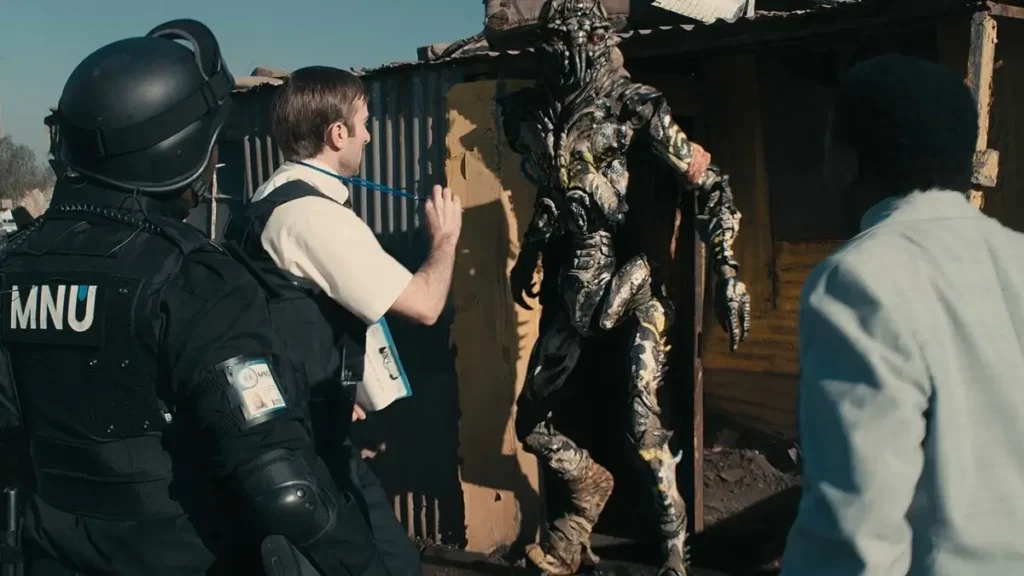 Sharlto Copley em cena do filme Distrito 9 (2009) durante operação da MNU em área dominada por extraterrestres