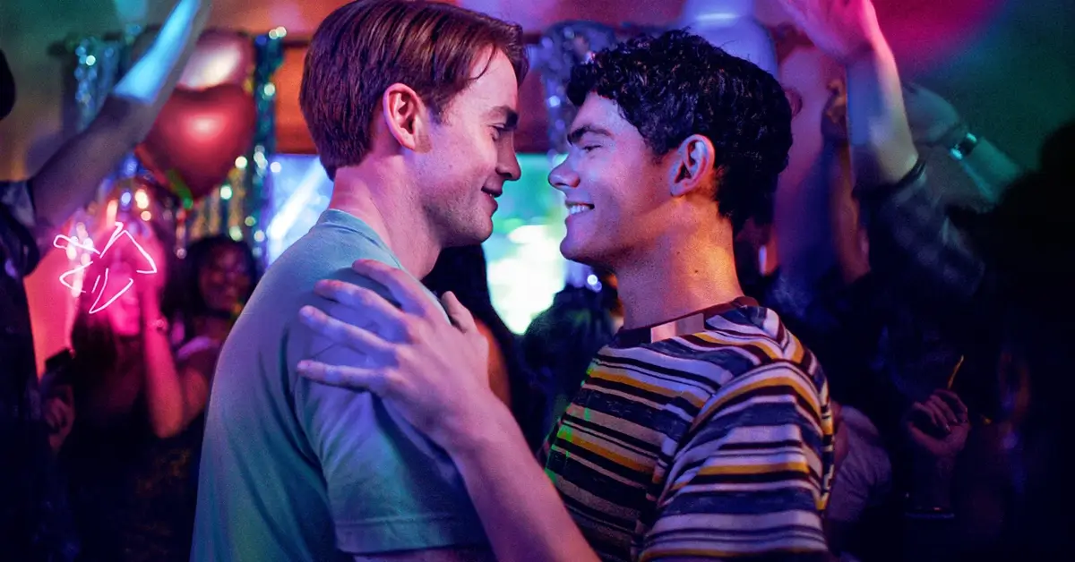 Joe Locke e Kit Connor dançam juntos e trocam sorrisos em uma festa iluminada por luzes coloridas em Heartstopper Para Sempre (2026), cena destacada no trailer de Heartstopper Para Sempre.