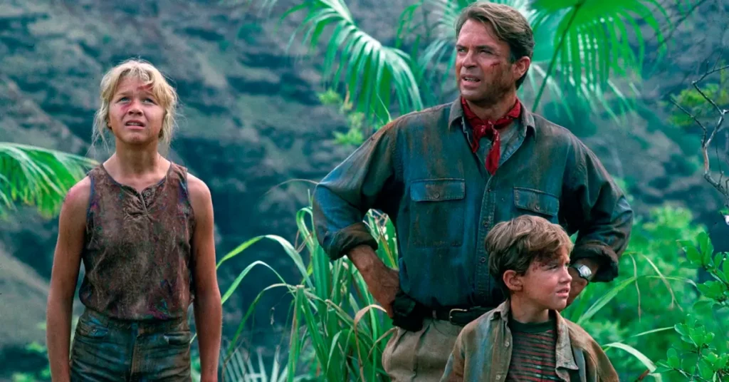 Sam Neill como Dr. Alan Grant ao lado de Lex e Tim Murphy em cena de Jurassic Park (1993), filme que marcou a carreira do ator e o consagrou como um dos grandes nomes do cinema.
