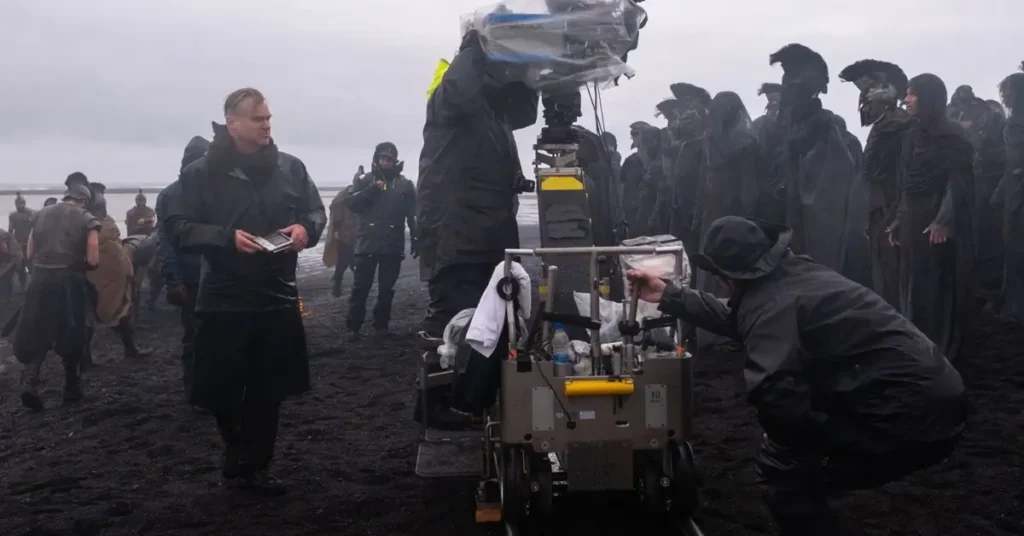 Christopher Nolan acompanha a equipe durante as filmagens de A Odisseia (2026) em uma praia de areia negra utilizada como locação do filme.