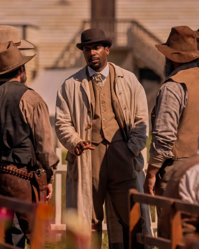 Jocko Sims como Dr. George Tann conversando com moradores em Uma Casa na Pradaria