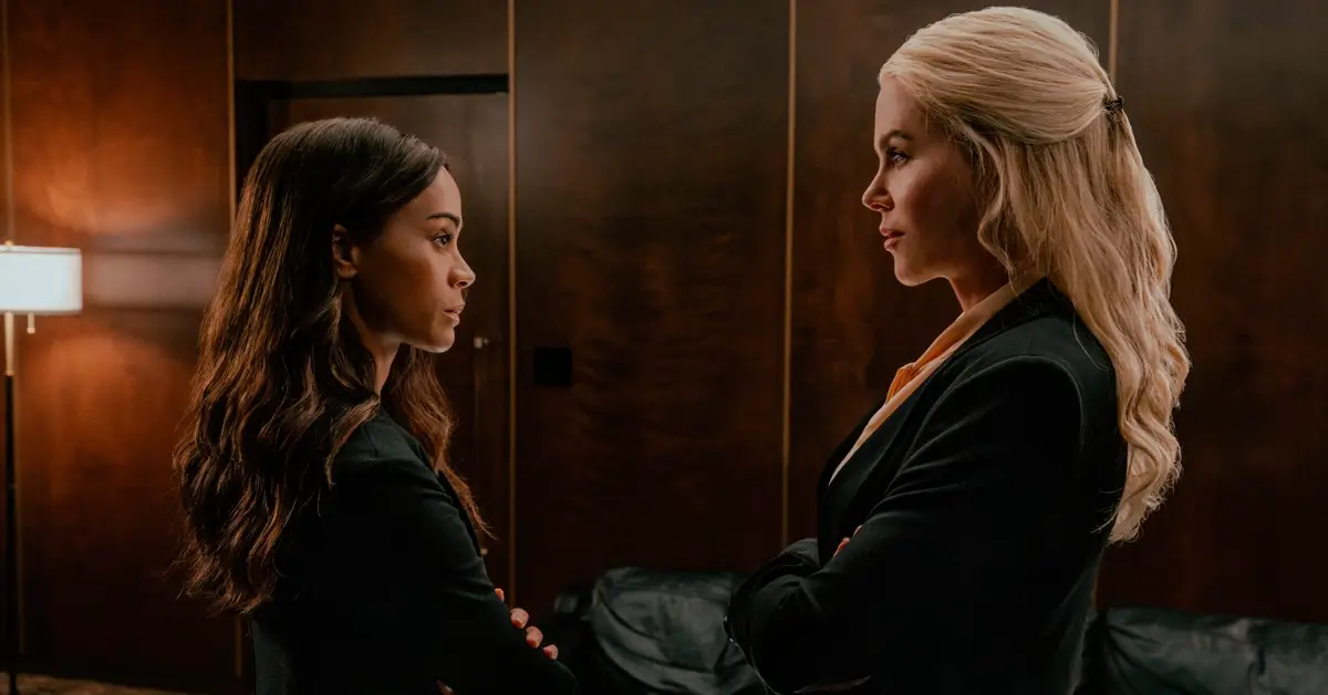 Zoe Saldaña e Nicole Kidman frente a frente em uma sala de reuniões na Temporada 3 de Operação Lioness, destacando o clima de tensão e estratégia da série.