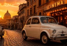Fiat Nuova 500 branco estacionado em uma rua histórica de Roma ao pôr do sol, ao lado de uma Vespa e de um cinema clássico, representando a ligação entre o automóvel e o cinema italiano.