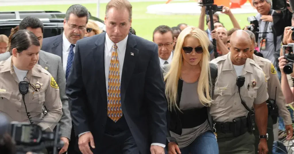 Lindsay Lohan acompanhada por agentes durante processo judicial em 2010