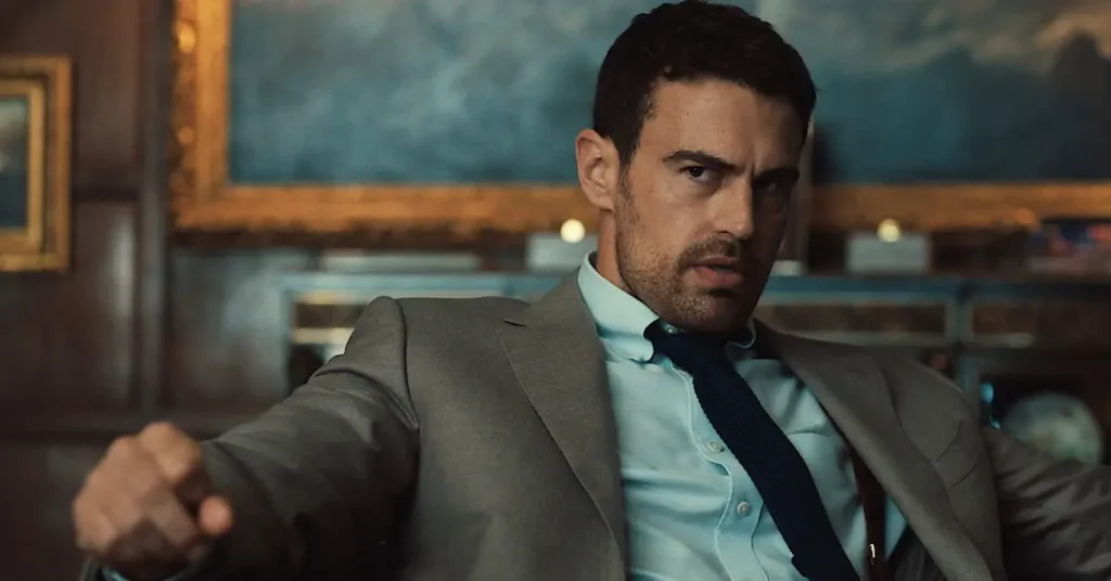 Theo James como Eddie Horniman em Magnatas do Crime: Temporada 2, usando terno e gravata em uma cena da série da Netflix.