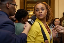 Roberta Rodrigues na segunda temporada de Cidade de Deus: A Luta Não Para, cercada por jornalistas durante uma entrevista.