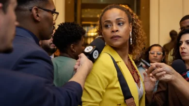 Roberta Rodrigues na segunda temporada de Cidade de Deus: A Luta Não Para, cercada por jornalistas durante uma entrevista.