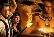 Elenco de A Múmia (1999) reunido em arte cinematográfica com Brendan Fraser, Rachel Weisz e Arnold Vosloo no deserto egípcio