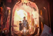 David McKenna, Beatrice Campbell e Emma Mackey em cena de Nárnia: O Sobrinho do Mago (2027), diante de um portal iluminado em um cenário fantástico.