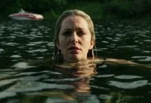 Jessica Rothe em cena no filme River (2026), com a atriz dentro de um lago.