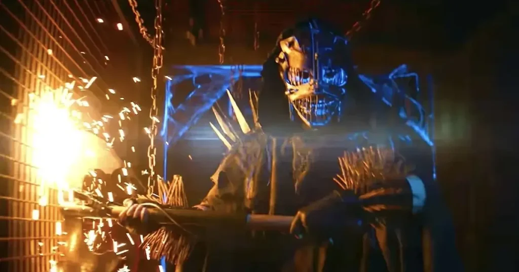 Assassino mascarado com motosserra em cena do trailer de Slayground, filme de terror da A24.