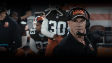 Christopher Meloni como o técnico Danny Roarke, usando boné do Cleveland Browns e headset à beira do campo na série The Land: Além do Jogo (2027).