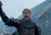 Xavier Molyneux as Erik Bloodaxe raises an axe in a scene from the series Bloodaxe (2027).